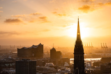 The sun shines through the church tower of St. Nikolai church in the city centre of Hamburg,...
