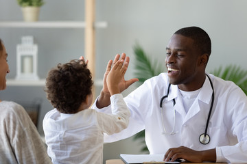 Smiling African American doctor giving high five to little boy