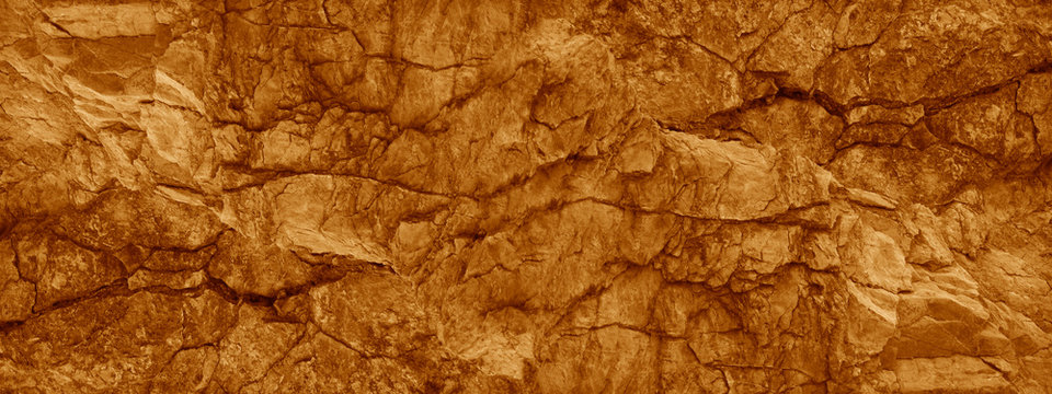 Brown orange rock background. Wide banner. Toned cracked mountains surface texture. Close-up. Stone background with copy space for design. Panoramic. 