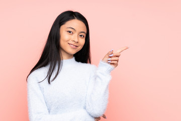 Teenager Chinese woman isolated on pink background happy and pointing up