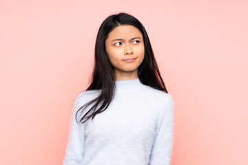 Fototapeta premium Teenager Chinese woman isolated on pink background making doubts gesture looking side
