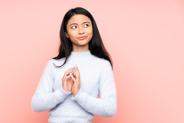 Teenager Chinese woman isolated on pink background scheming something