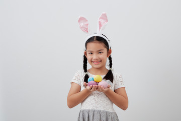 little child girl with easter bunny ears holding egg