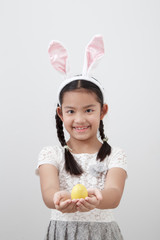 little child girl with easter bunny ears holding egg