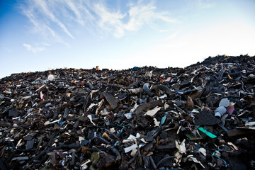 Hałda zmieszanych odpadów na wysypisku śmieci na tle niebieskiego nieba - obrazy, fototapety, plakaty