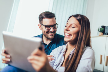 Happy young couple enjoying time online on digital tablet.