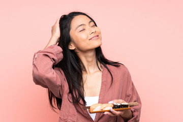 Teenager Asian girl eating sushi isolated on pink background laughing