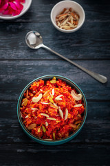 Gajar ka halwa is a sweet dessert pudding from India made from carrot, served in a bowl. Garnished with cashew, almond and pistachio nuts.