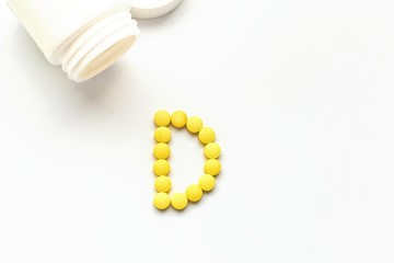 The concept of pills vitamins for treatment. Group D vitamin is laid out by yellow pills on a white isolate background. Water soluble vitamins. Lipovitamins. The complex of vitamins. Copy space.