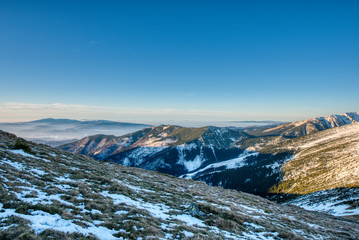 Fototapeta na wymiar Low winter snow cover in mountains at sunrise and fog in valley, Nizke Tatry Chopok, Low Tatras