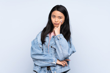 Teenager Chinese woman isolated on blue background and thinking