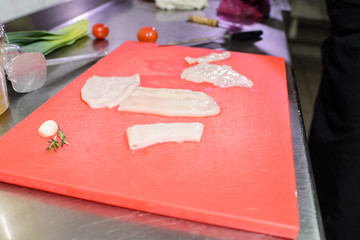 Slicing fresh squid on a cutting board. Delicious seafood for restaurant guests.