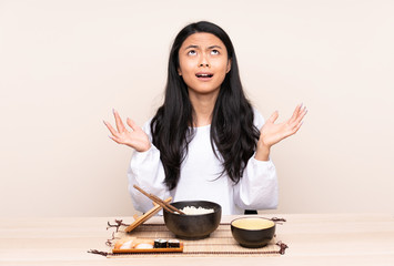Teenager Asian girl eating asian food isolated on beige background frustrated by a bad situation
