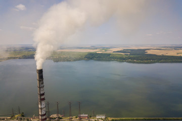 Aerial view of high chimney pipes with grey smoke from coal power plant. Production of electricity with fossil fuel.