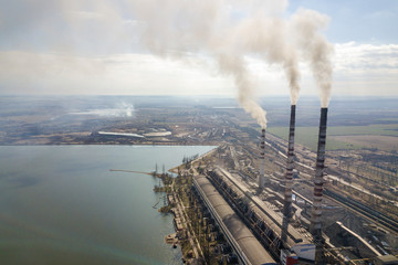 Tall pipes of power plant, white smoke on rural landscape, lake water and blue sky copy space...