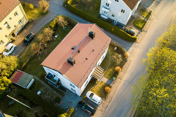 Aerial view of residential houses with red roofs and streets with parked cars in rural town area. Quiet suburbs of a modern european city.