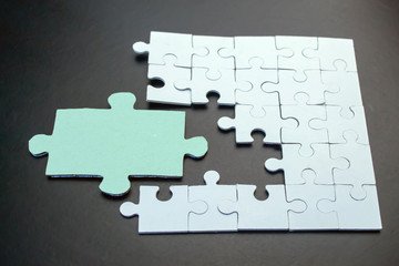 White puzzles among them one big green puzzle on a black background close-up