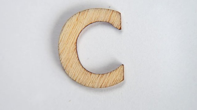 Dancing letter C of the English alphabet. Wooden letter in motion on a white background. Writing form concept. Stop motion.