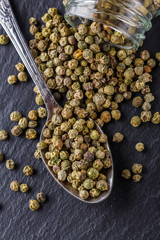 green peppercorns on dark slate stone background