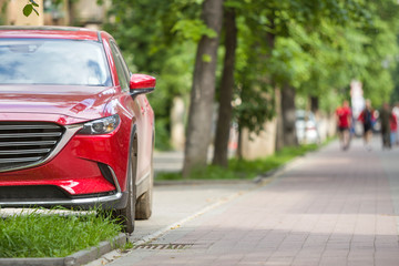 Car parked in pedestrian zone under trees on city street with walking people on summer day.