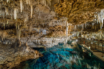 Fototapeta na wymiar Stalactites and stalagmites surrounded by crystal clear turquoise waters within the Fantasy and Crystal caves. Hamilton Parish, Bermuda. 