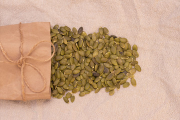 pumpkin seeds in a paper bag on natural linen. pumpkin seeds vitamins of group b and magnesium.