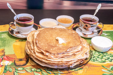 On the table, tea with pancakes, sour cream and jam for the Maslenitsa holiday, which is celebrated in Russia at the end of winter.