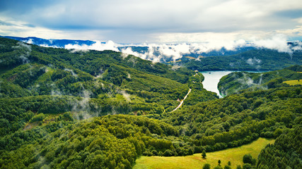 Clouds of fog after summer rain. Landscape with lake and mountain woodland