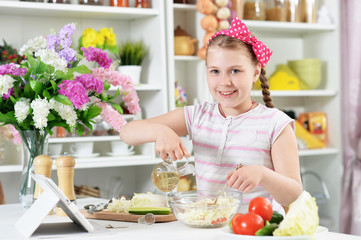 Cute girl preparing delicious fresh salad in kitchen