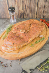 Raw steak with a round bone in the center, a large piece in a marinade, a butcher's knife.