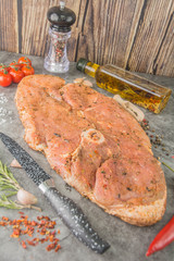 Raw steak with round bone in the center, a large piece in the marinade, knife, spices.