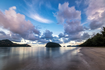 long exposure of a beach in Thailand at night with islands, clouds and the moon in the frame