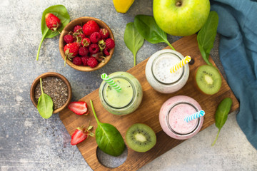 The concept of a healthy diet and diet. Green Detox mixed smoothies vegetable and fruit with organic ingredients on a stone concrete worktop. Top view flat lay background.