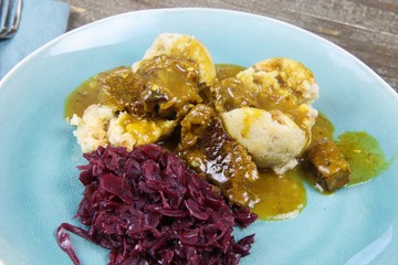 Typical german hearty meal: closeup of dumplings with brown sauce, red cabbage, goulash meat on...