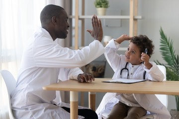African American father playing doctor with son, giving high five