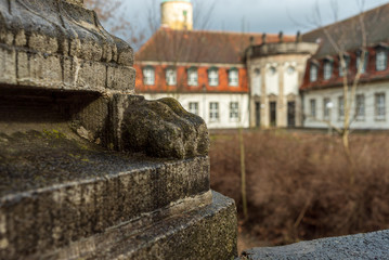 Krallenfuß an altem Brückenpfeiler mit historischem Gebäude im Hintergrund