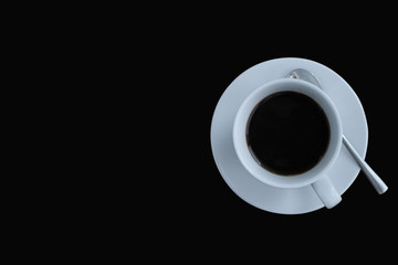 Top view of a white coffee cup with saucers and spoons  on the right side of the black background, there is a space  for lettering.