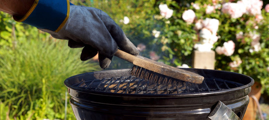 scrubbing utensil used for cleaning a dirty grill. Male hand with gloves cleans round grill with...