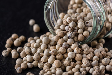 white peppercorns on dark slate stone background