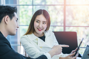 Smiling Asian business woman listening colleague comment and pointing at tablet in meeting. Smart coworkers discuss, brainstorm for new project planning. Communication and business concept, Daylight