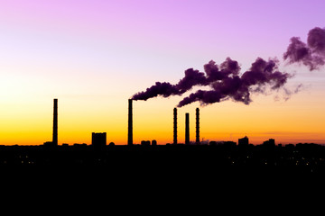 concept of environmental pollution smoke from factories at sunset. silhouettes of factories and factories in the evening
