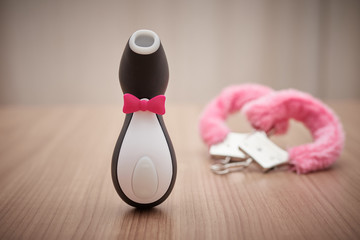 satisfyer pro penguin, the most famous dildo for women. with some pink handcuffs in the background