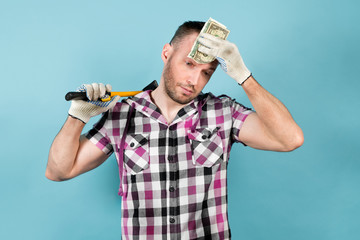 dirty worker holds tools in one hand and wipes sweat from his forehead