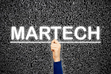 Woman showing MARTECH sign, on wire dark background. Martech is the blending of marketing and technology.