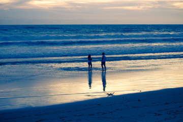 Fototapeta na wymiar people walking along the beach at sunset by the sea, beautiful evening landscape