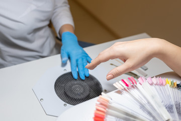 Female hand with color palette at beauty salon waiting for a manicure procedure.