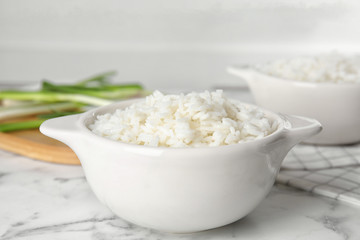 Bowl with tasty cooked rice on marble table, closeup