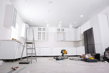 Renovated kitchen interior with stylish furniture, refrigerator and maintenance equipment