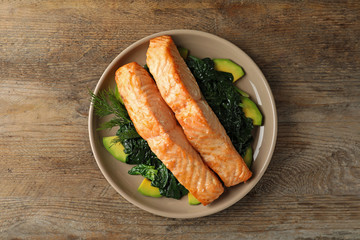 Tasty salmon with spinach and avocado on wooden table, top view