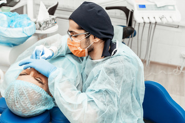 A young male dentist doctor treats a patient. Medical manipulations in dentistry, surgery....